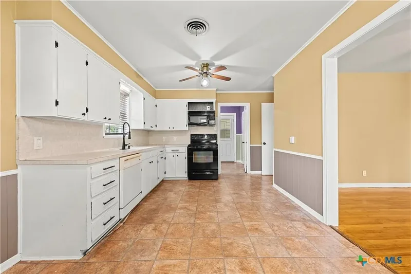 Current kitchen with white cabinetry and tile floor